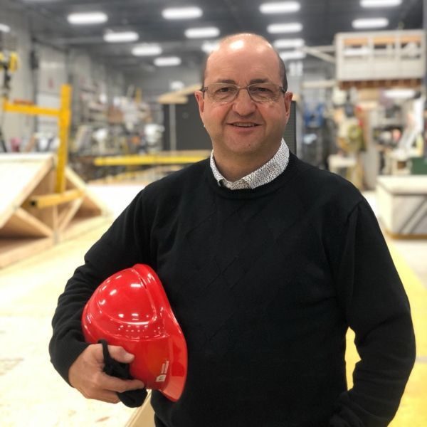 Maurice Poirier, directeur général, un casque rouge à la main dans l'usine