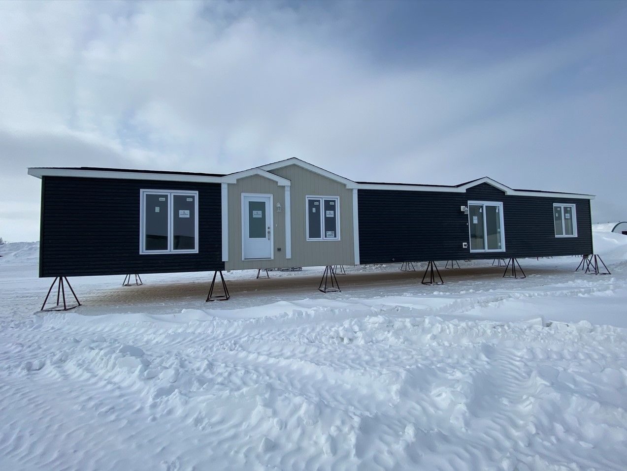 Une unimodulaire Maison Nordique livrée sur la neige, posée sur ses appuis, revêtement noir et gris